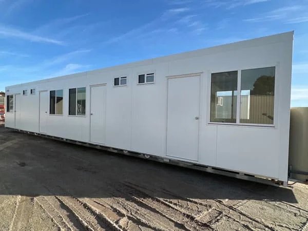 Long multi-section bunkhouse building under a clear blue sky